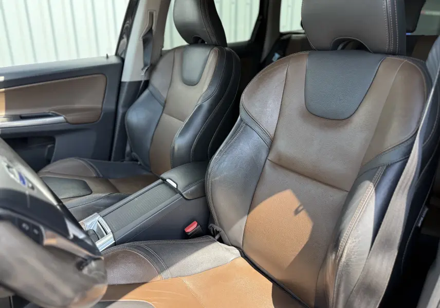 Vue rapprochée des sièges avant en cuir bicolore marron et noir du Volvo XC60 2016, côté conducteur et passager.