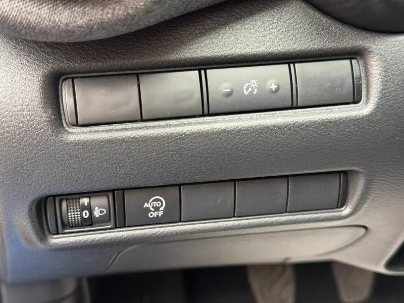 Gros plan sur les commandes de réglage de luminosité et d'allumage automatique dans l'habitacle noir du Nissan Juke bleu.