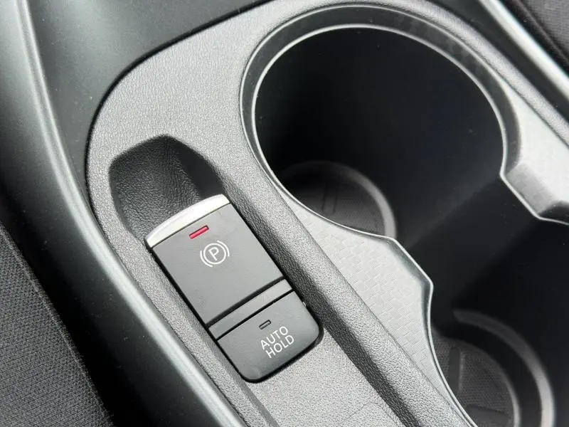 Gros plan sur la commande de frein à main électrique et porte-gobelets noirs à l'intérieur du Nissan Juke Bleu Magnétique Spéciale 2025.