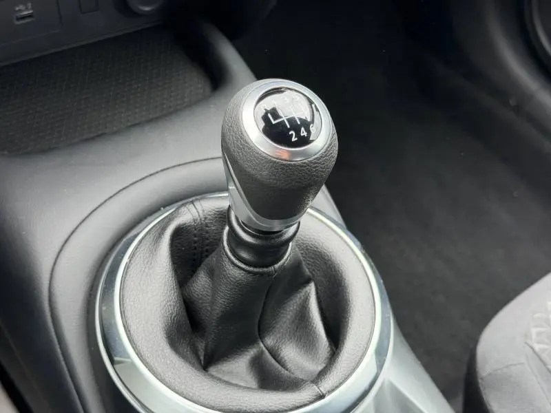 Gros plan sur le levier de vitesse manuel noir du Nissan Juke 2025, entouré d'un cerclage chromé intérieur.