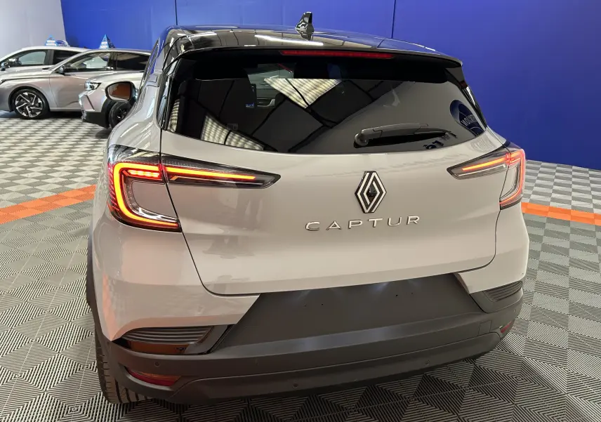 Vue arrière du Renault Captur gris Rafale avec feux LED allumés dans un showroom au sol à damier.