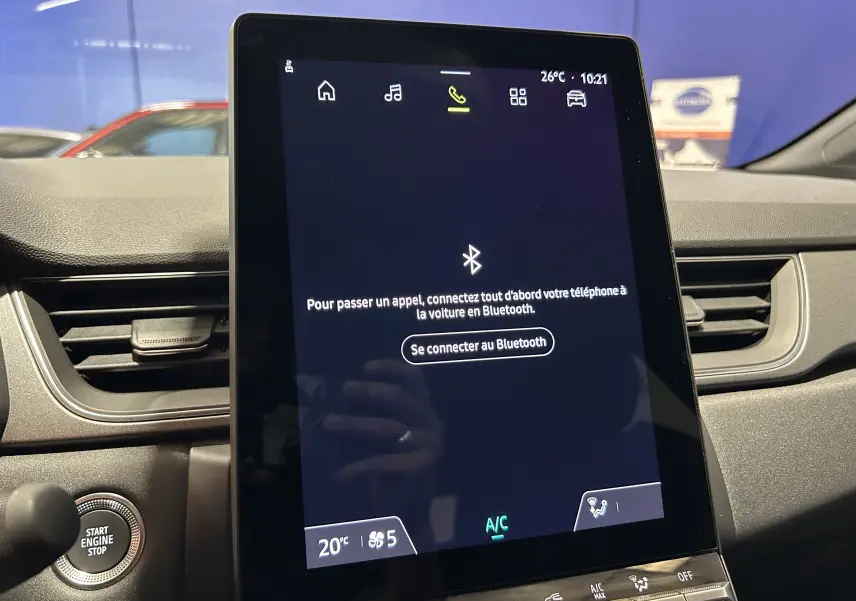Écran tactile central allumé avec interface Bluetooth, tableau de bord et bouton start/stop du Renault Captur gris Rafale.