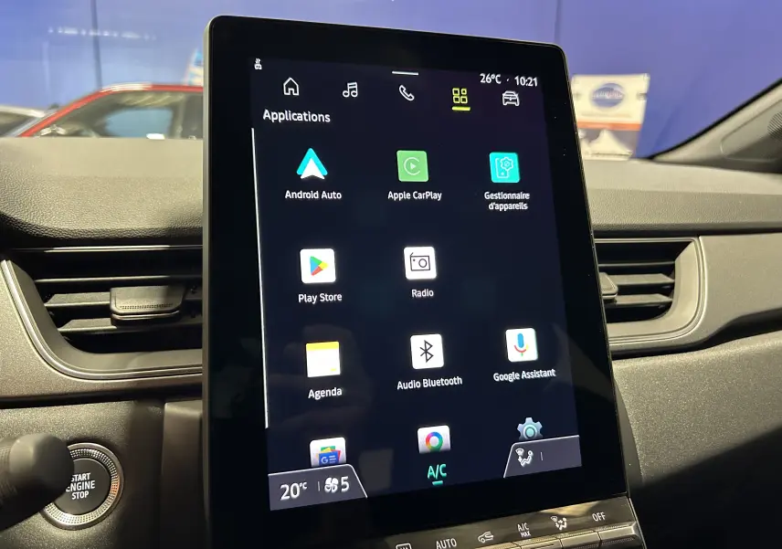 Vue rapprochée de l’écran tactile central du tableau de bord du Renault Captur gris Rafale, affichant les applications connectées.