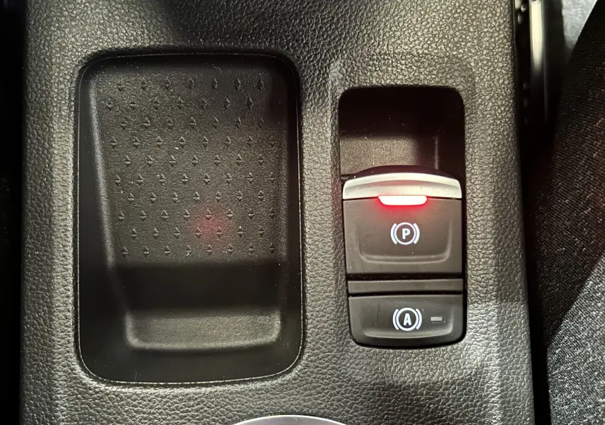 Gros plan sur la console centrale du Renault Captur gris Rafale, montrant le frein à main électronique avec témoin rouge allumé.