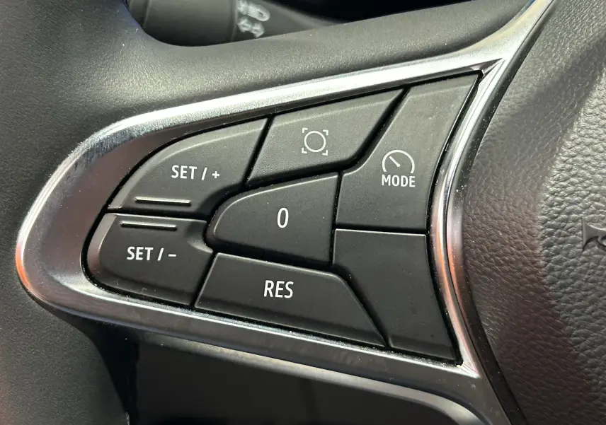 Gros plan sur les commandes noires du volant côté gauche du Renault Captur gris Rafale, boutons de régulateur de vitesse.