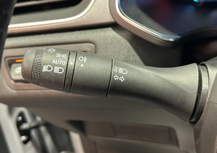 Gros plan sur la commande des feux et clignotants du tableau de bord d’un Renault Captur gris Rafale 2025.