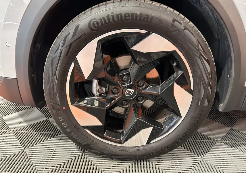 Gros plan sur la roue avant droite du Renault Captur gris Rafale, avec jante noire et argentée au design géométrique.