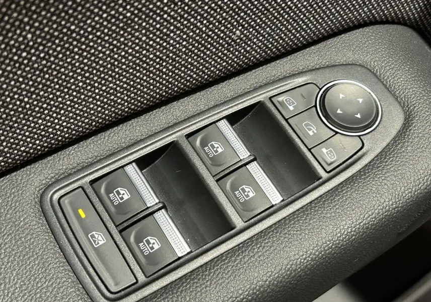 Gros plan sur les commandes de lève-vitres et rétroviseurs électriques côté conducteur du Renault Captur gris Rafale.