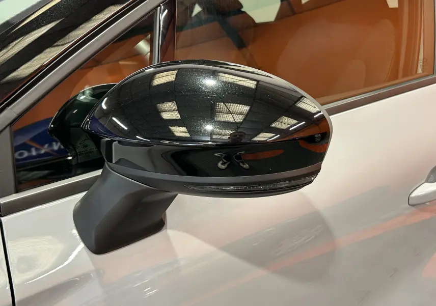 Rétroviseur noir brillant côté gauche du Renault Captur gris Rafale, avec reflet de l'éclairage intérieur.