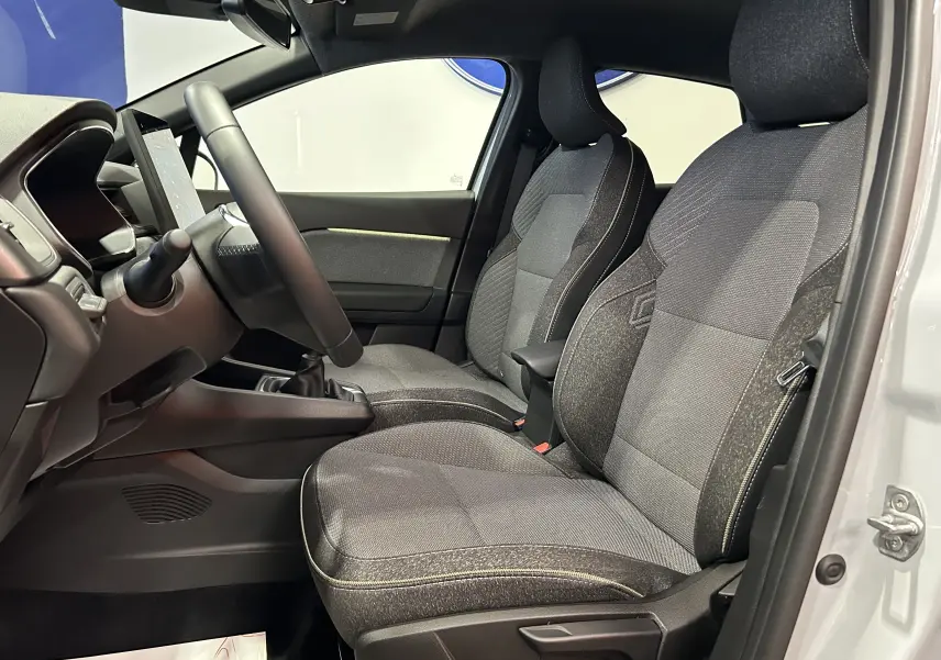 Vue intérieure côté conducteur du Renault Captur gris Rafale, montrant les sièges en tissu et le volant avec boîte manuelle.