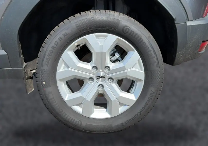 Gros plan sur la roue arrière droite du Dacia Duster gris schiste, jante alu à design hexagonal.