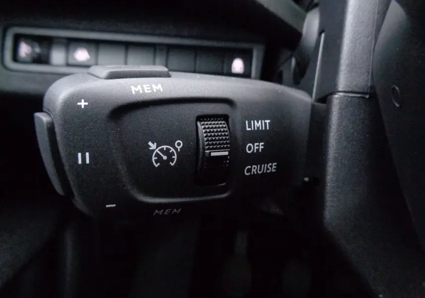 Gros plan sur la commande de régulateur de vitesse du Peugeot 5008 noir perle métal, avec molette et boutons MEM, LIMIT, OFF, CRUISE.
