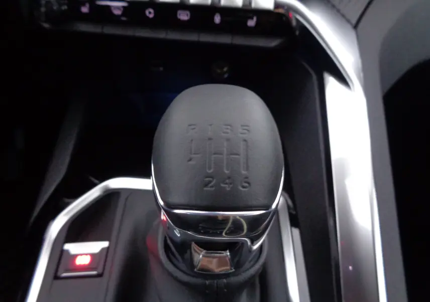 Le levier de vitesses manuel noir et chrome du Peugeot 5008 2023, vue rapprochée de la console centrale.