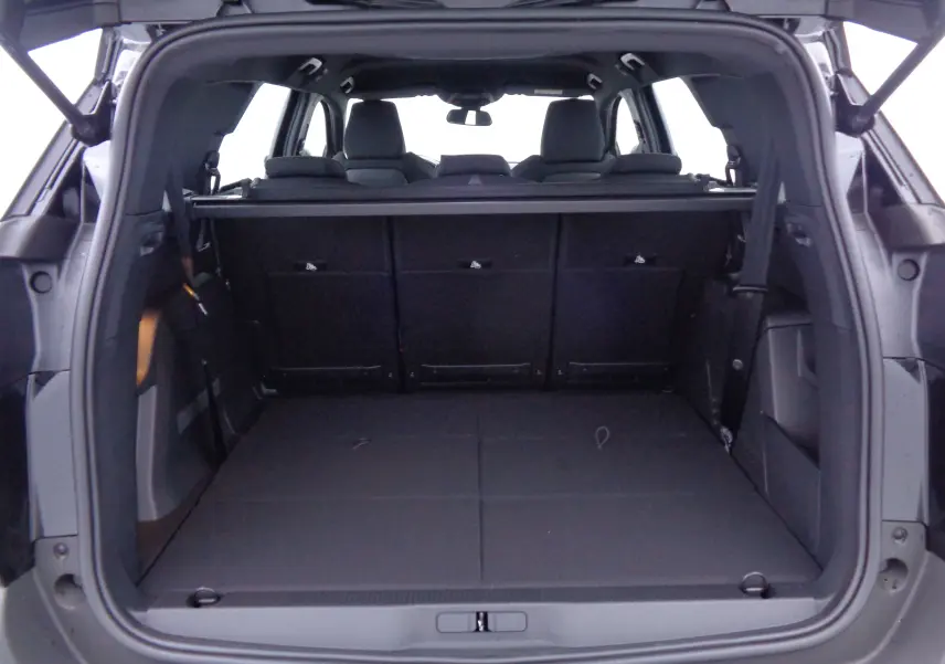 Coffre ouvert vu de l'arrière d'un Peugeot 5008 noir perle métal, montrant l'espace de chargement et les sièges arrière rabattus.