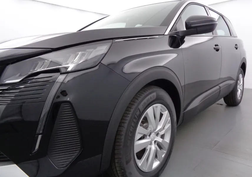 Vue 3/4 avant droit d'un Peugeot 5008 noir perle métal avec phares LED et jantes alliage 17 pouces.