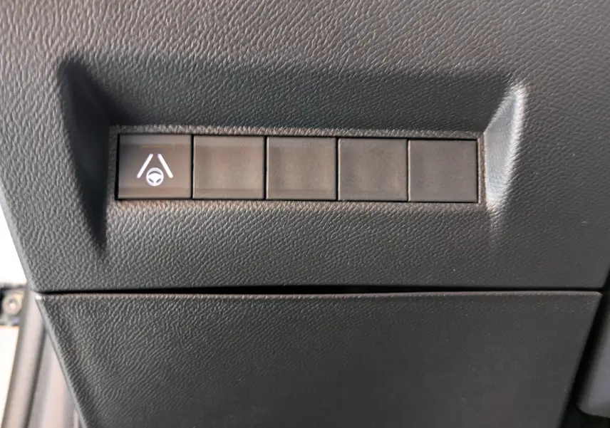 Gros plan sur le bouton d'assistance au maintien de voie dans l'habitacle noir d'une Peugeot 208 Hybrid 145ch GT 2024.