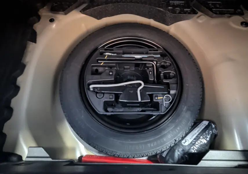 Roue de secours et kit de réparation logés dans le coffre d'une Peugeot 208 Hybrid 145ch gris Artens 2024.