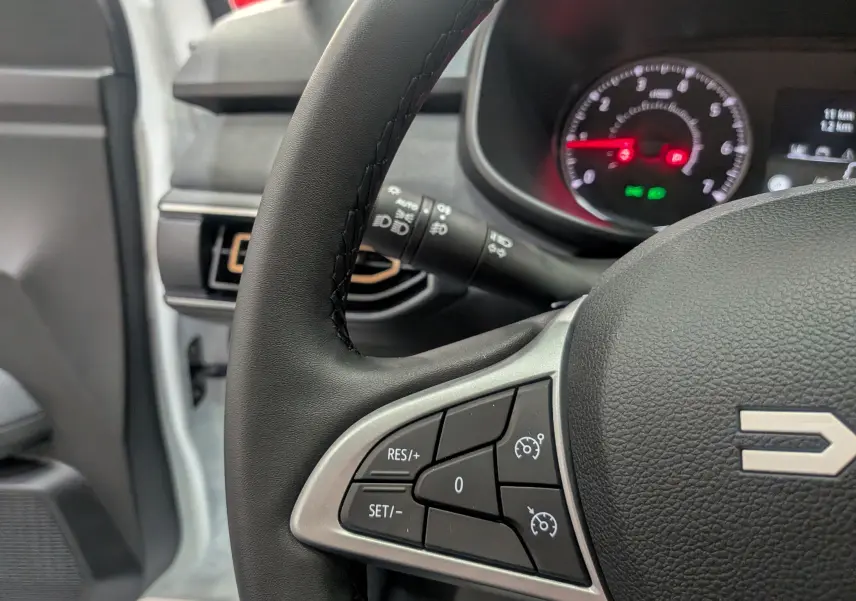 Gros plan sur le volant noir du Dacia Sandero Stepway 2025, montrant les commandes de régulateur de vitesse côté gauche.