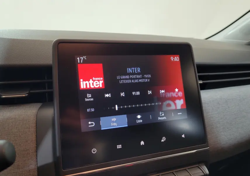 Écran tactile central affichant la radio France Inter dans l'habitacle d'une Renault Clio bleu, vue de face.