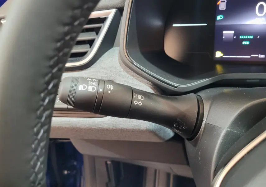 Gros plan sur la manette de phares et clignotants à gauche du volant dans le tableau de bord d'une Renault Clio bleu 2025.