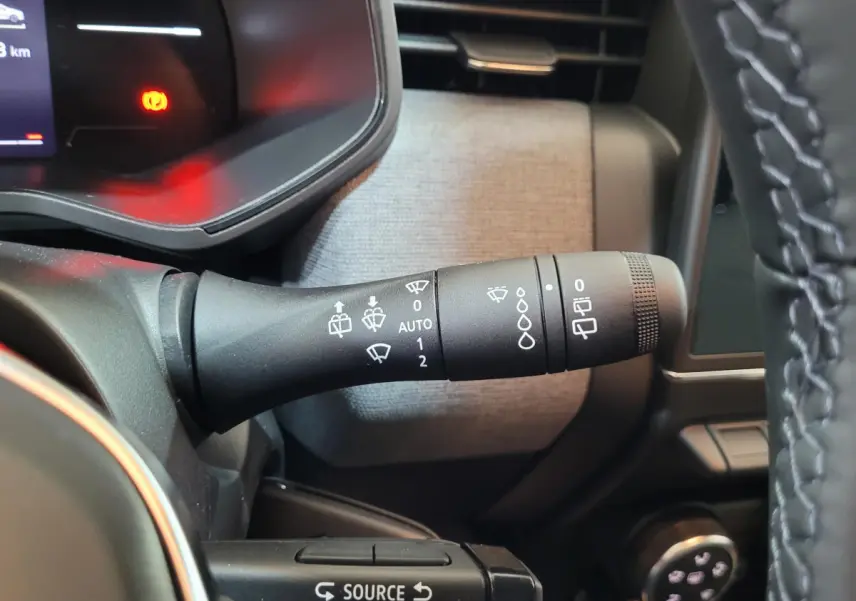 Gros plan sur la manette d'essuie-glace à gauche du volant dans l'habitacle d'une Renault Clio bleu 2025.