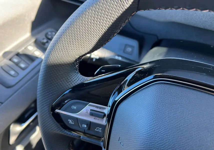 Gros plan sur le volant cuir multifonctions côté gauche du Peugeot Rifter 2025, avec commandes intégrées et finition noire brillante.