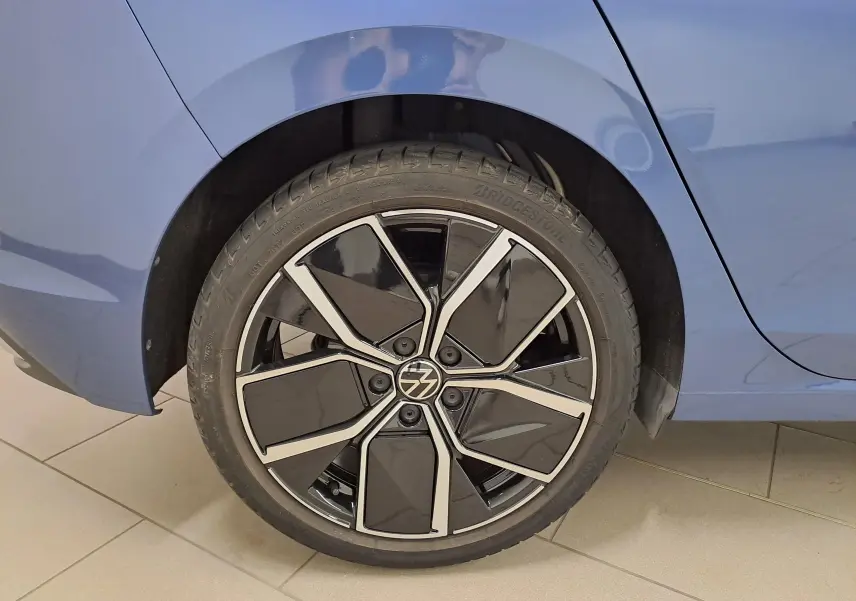 Gros plan sur la roue arrière droite d'une Volkswagen Golf 1.5 eTSI Bleu Anémone avec jante noire et argentée.