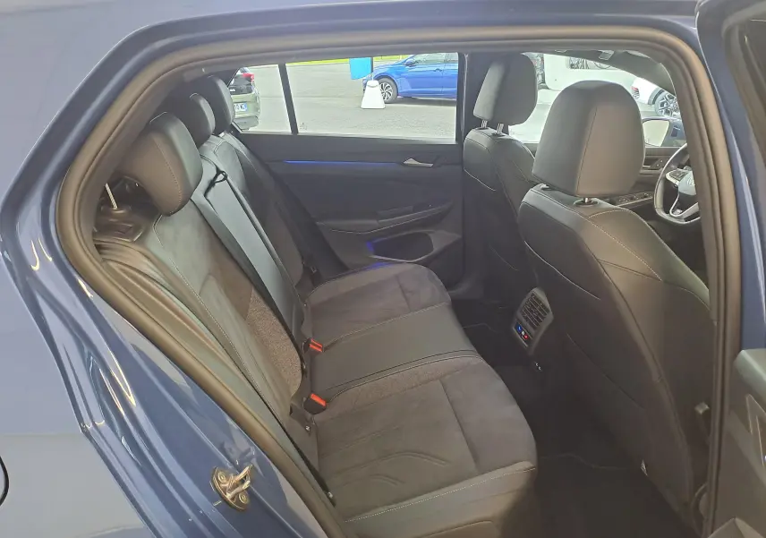Vue intérieure côté gauche montrant les sièges arrière en tissu et cuir d'une Volkswagen Golf Bleu Anémone 2024.