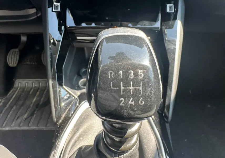 Gros plan sur le levier de vitesses manuel noir de la Peugeot 208 1.2 100ch, entouré de la console centrale noire.