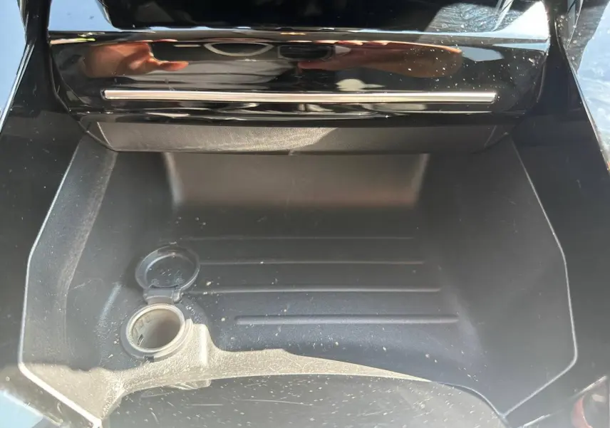 Compartiment de rangement intérieur ouvert avec prise 12V visible sur Peugeot 208 gris Selenium 2025.