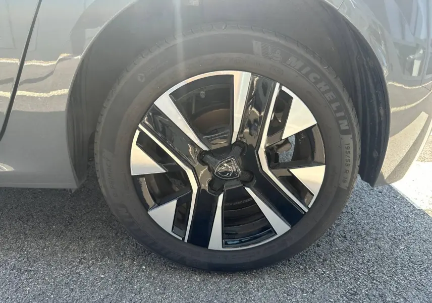 Gros plan sur la jante alu noire et argentée d'une Peugeot 208 gris Selenium, côté droit arrière.