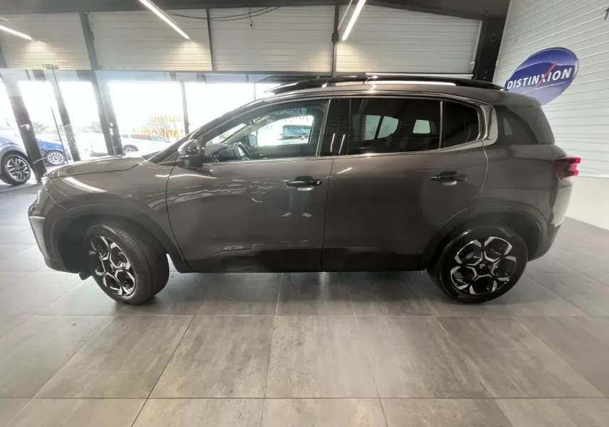 Vue de profil côté gauche d'un Citroën C5 Aircross gris platinium avec jantes alliage noires et toit noir brillant.