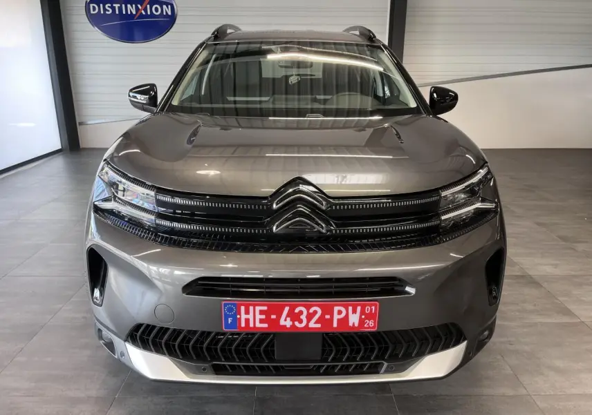 Vue frontale d'un Citroën C5 Aircross gris platinium avec calandre noire brillante et plaque d'immatriculation rouge.