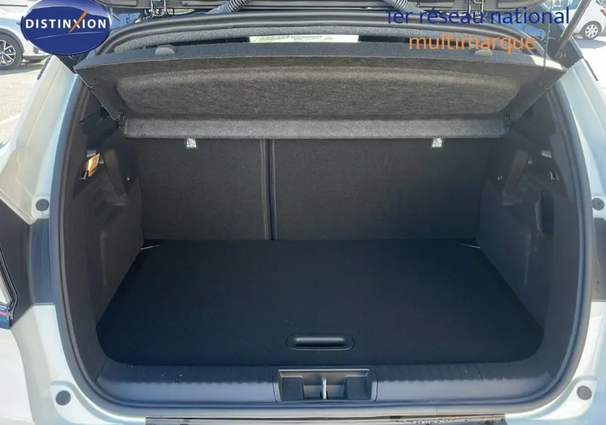 Coffre ouvert vu de l'arrière d'un Renault Captur E-Tech hybride blanc nacré avec toit noir, intérieur de coffre noir.