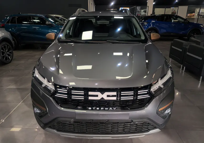 Vue avant rapprochée d'une Dacia Sandero Stepway TCe 110 Gris Schiste avec calandre noire et détails cuivrés.