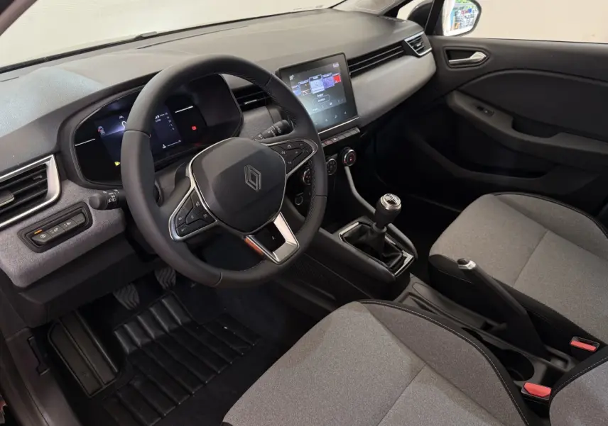 Intérieur Renault Clio 2025 vu côté conducteur, volant cuir, écran tactile central et sièges gris clair.
