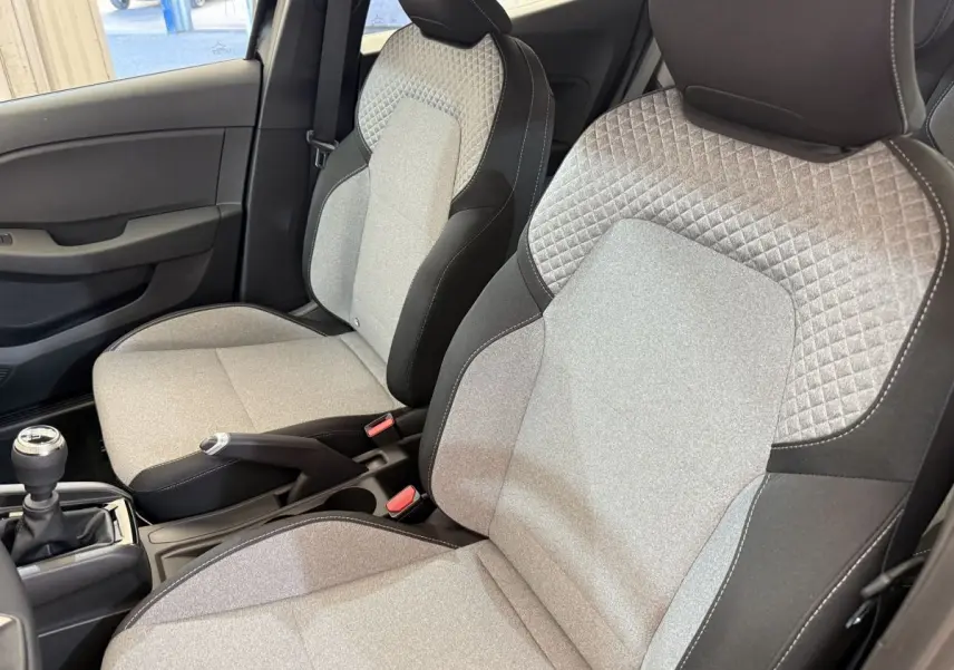 Vue intérieure rapprochée des sièges avant gris clair et noir de la Renault Clio Evolution Blue dCi 100 2025.