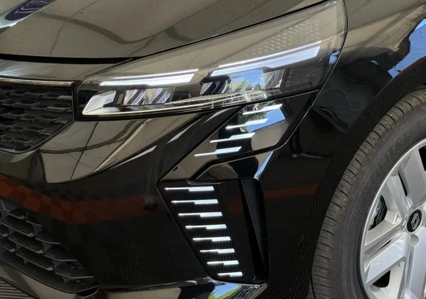 Gros plan sur le phare avant droit et la roue d'une Renault Clio noire 2025 avec feux LED distinctifs.