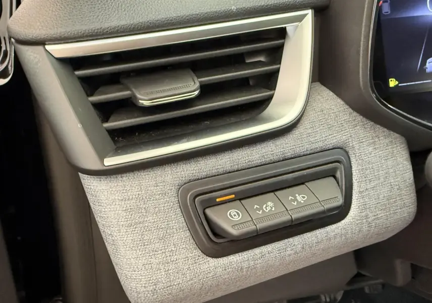 Gros plan sur la commande d'éclairage et la sortie d'air côté gauche du tableau de bord gris clair d'une Renault Clio noire 2025.