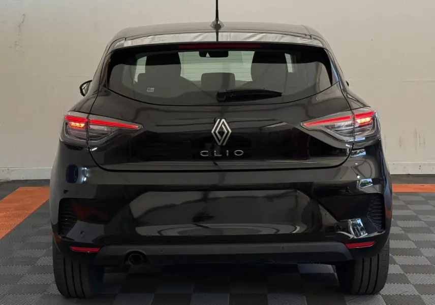 Vue arrière d'une Renault Clio noire 2025 avec feux LED allumés dans un intérieur neutre.