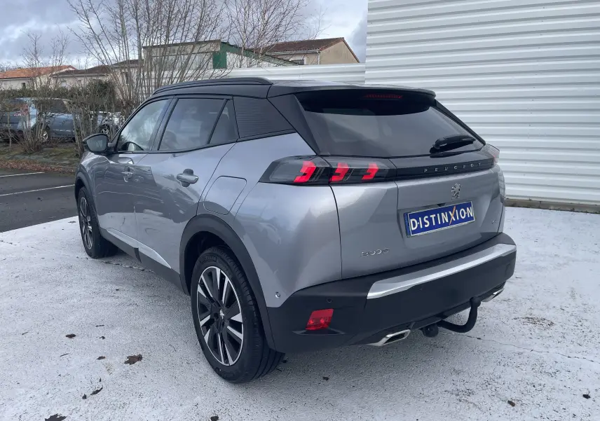 Peugeot 2008 gris Artense vue 3/4 arrière droit, toit noir, feux arrière LED et attelage visible.