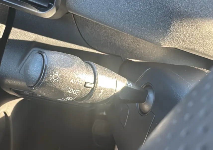Gros plan sur la commande des feux à gauche du volant dans l’habitacle du Peugeot Rifter noir perla nera.