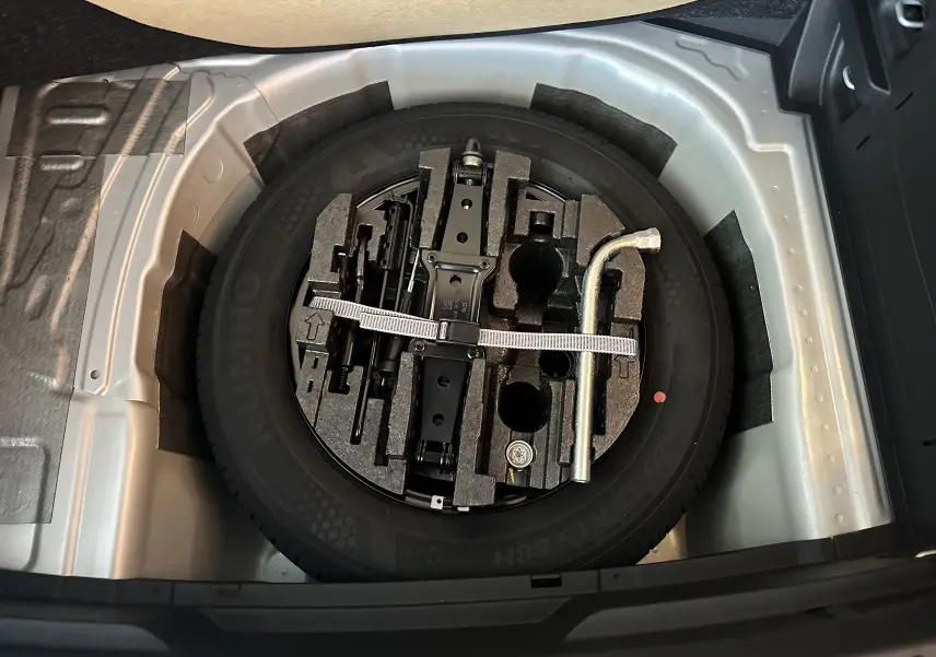 Vue plongeante sur la roue de secours et les outils de bord dans le coffre d'une Skoda Fabia gris argent 2023.