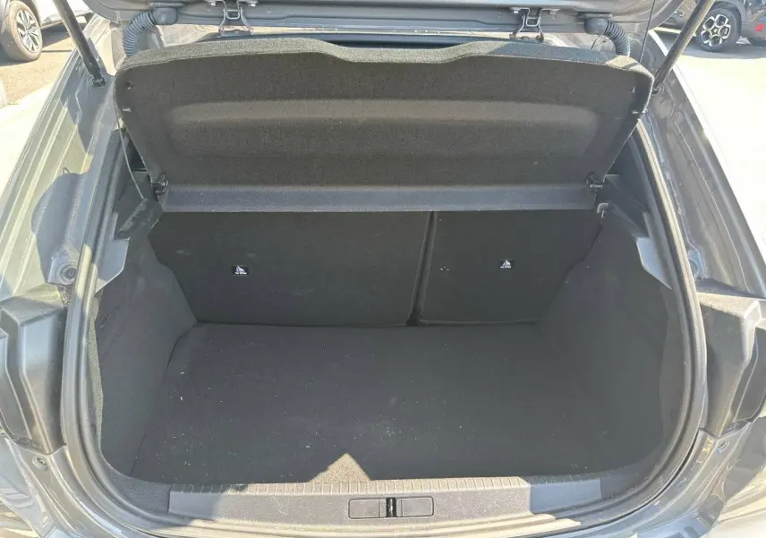 Coffre ouvert vu de l’arrière d’une Peugeot 208 1.2 100ch gris Selenium, montrant l’espace de chargement vide.