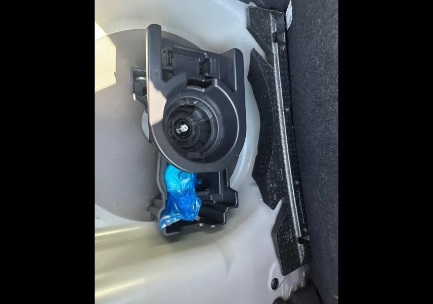 Vue rapprochée du coffre de la Peugeot 208 2025 gris Selenium, montrant le rangement et l’emplacement de la roue de secours.