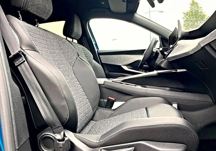 Vue intérieure côté conducteur de la Peugeot 3008 2025 bleu, sièges tissu et cuir avec console centrale moderne.