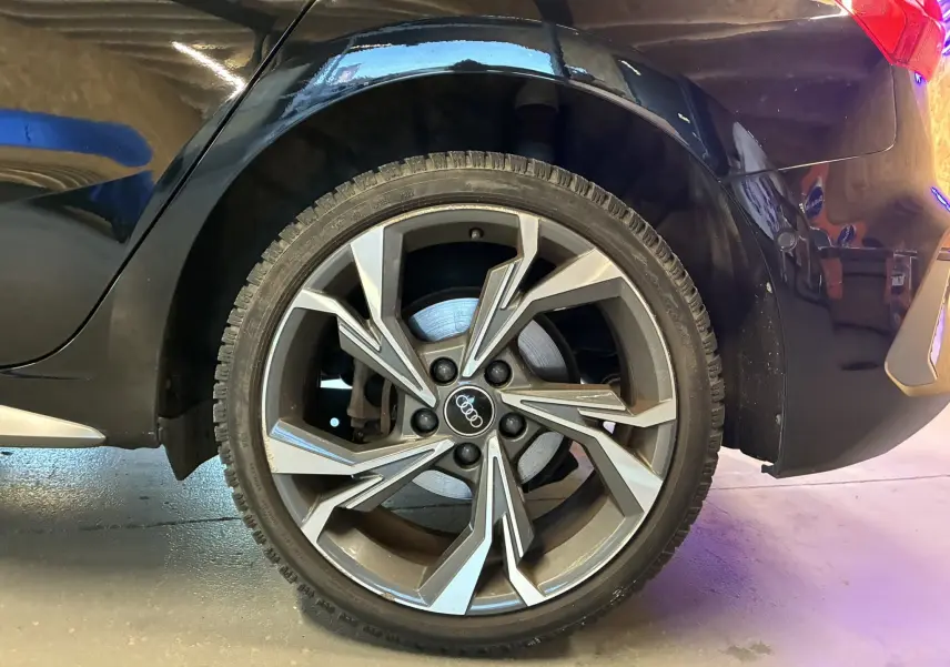 Vue rapprochée du côté arrière droit d'une Audi A3 Sportback noire 2022, mettant en valeur l'aile et le feu arrière.