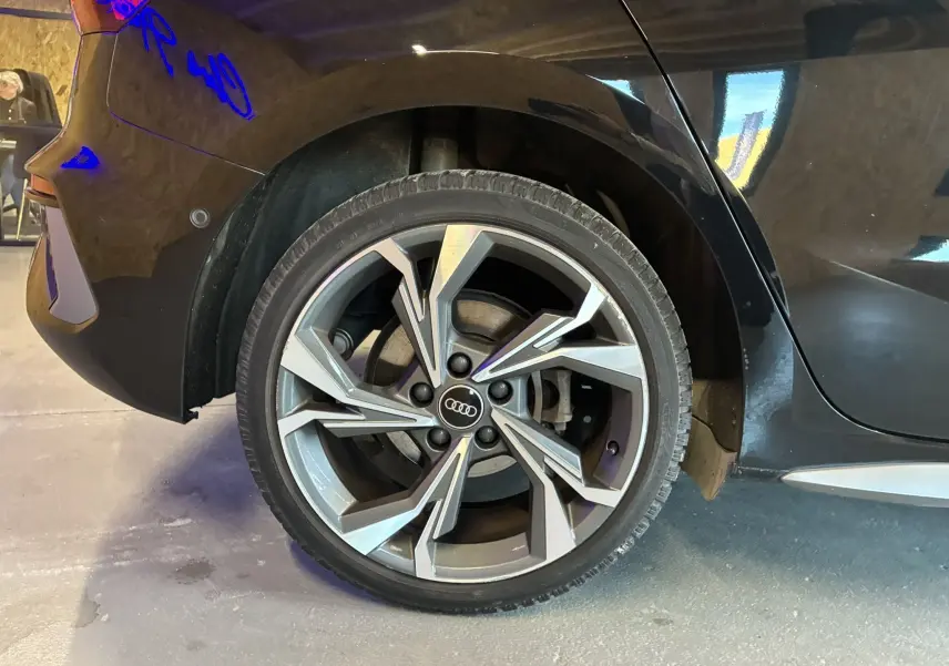 Gros plan sur la roue arrière droite noire d'une Audi A3 Sportback 2022 avec jante alliage au design moderne.