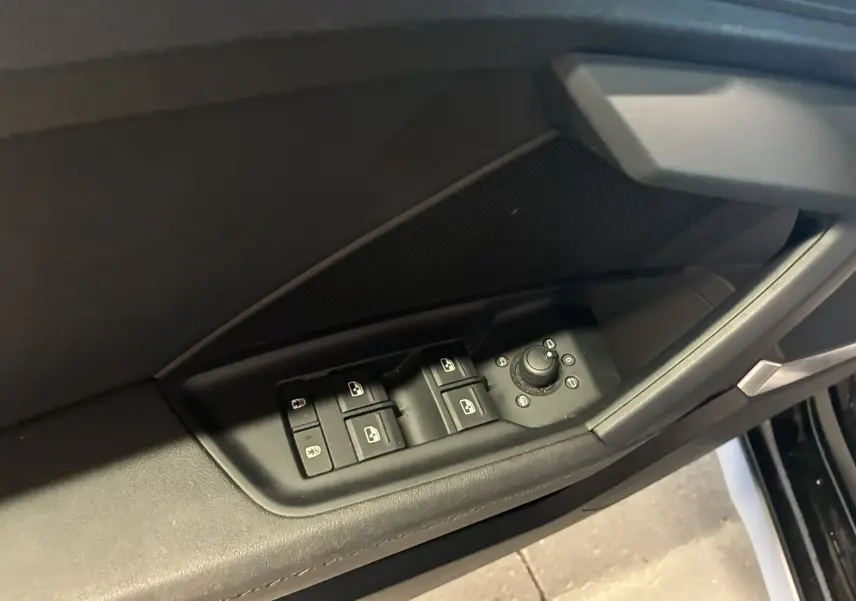Commandes des vitres et réglage des rétroviseurs côté conducteur de l'Audi A3 Sportback noir 2022 en gros plan intérieur.