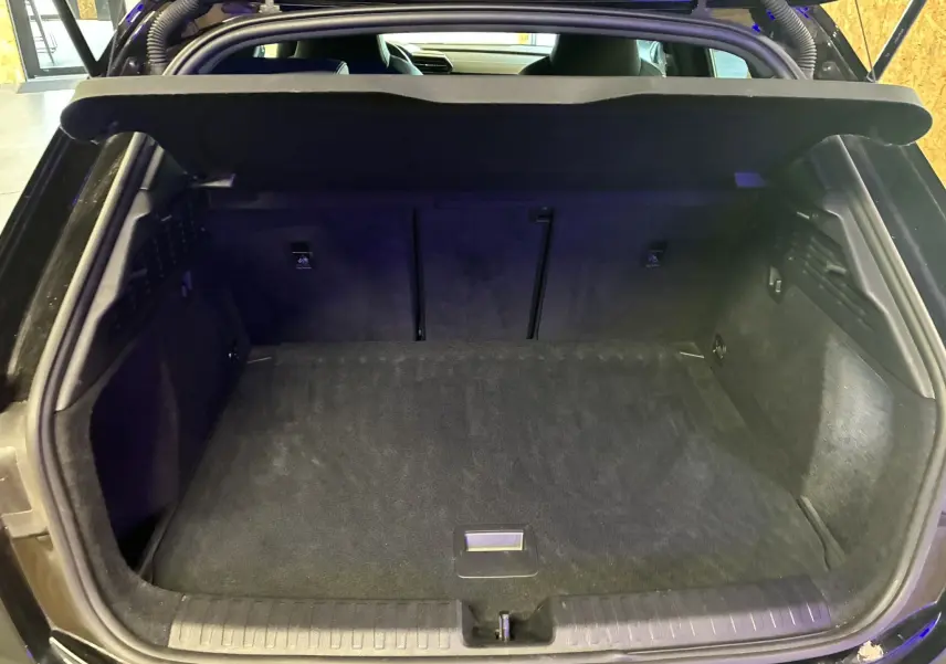 Coffre ouvert vu de l'arrière d'une Audi A3 Sportback noire, montrant un espace de rangement propre et spacieux.